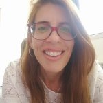 Woman smiling with light brown long hair and red glasses