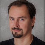 Man with dark brown, short hair, moustache and trimmed beard.