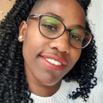 Smiling professional woman with long black curly hair and glasses